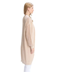 Woman wearing a beige cardigan and white pants on a white background