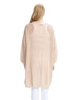 Person wearing a beige cardigan and white pants on a white background