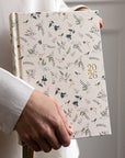 Person holding a floral-patterned notebook with '2026' on a plain background