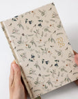 Floral-patterned notebook held by hands on a white background