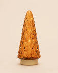An amber glass Christmas tree-shaped decorative light or lamp with a textured, diamond-patterned surface and a gold-toned circular base, set against a plain off-white background.