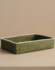 Green woven rectangular basket on a beige background.