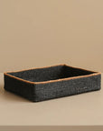 Rectangular black woven basket on a beige background