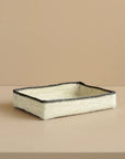 Rectangular woven tray with black rim on a beige background