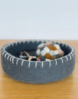 Blue felted bowl with decorative items on a wooden surface