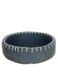 Gray felted bowl with white stitching on a wooden surface