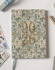 Floral notebook with '2026' design on a light surface with stationery items.