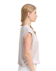 Woman wearing a light pink blouse and white pants on a white background