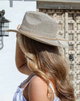 Woman wearing a straw hat in front of a textured wall.