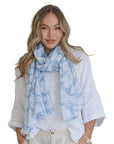 Woman wearing a light blue floral scarf with a plain background