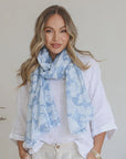 Woman wearing a light blue floral scarf with a plain background