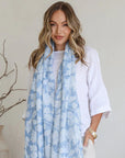 Woman wearing a light blue floral scarf in a minimal indoor setting