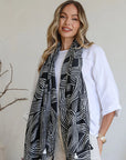 Woman wearing a black and white patterned scarf in a minimalistic room.
