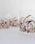 Three glass tumblers with floral and bird design on a white surface