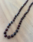 Necklace with dark red beads on a light wooden surface
