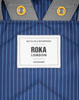 Close-up of a Roka London label on a blue striped fabric background