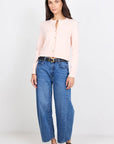 Woman wearing a light pink blouse and blue jeans on a white background