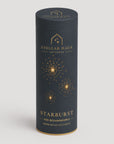 A tall cylindrical product box for Stellar Haus Agtearoa Starburst USB rechargeable warm white LED lights, featuring a dark charcoal gray body with gold foil starburst graphics and text, set against a light gray background.