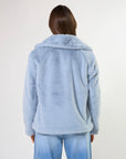 Person wearing a light blue fluffy jacket on a white background