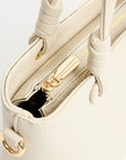Close-up of a beige handbag with gold accents on a white background