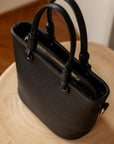 Black handbag on a wooden surface with a neutral background