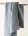 Gray blanket draped over a wooden stick on a light background