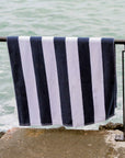 Navy and white striped towel hanging on a railing by the water.