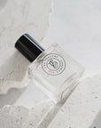 Perfume bottle with black cap on a textured white surface