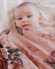 Baby wrapped in a floral blanket on a soft surface