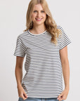 Woman wearing a black and white striped t-shirt and blue jeans on a light gray background
