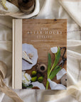 Book titled 'The After Hours Stylist' on a decorative surface with flowers and ribbons.