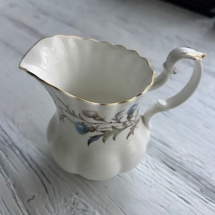 White ceramic pitcher with floral design on a wooden surface