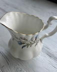 White ceramic pitcher with floral design on a wooden surface