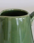 Green ceramic pitcher on a plain background