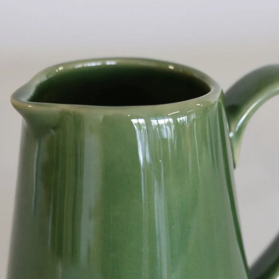 Green ceramic pitcher on a plain background