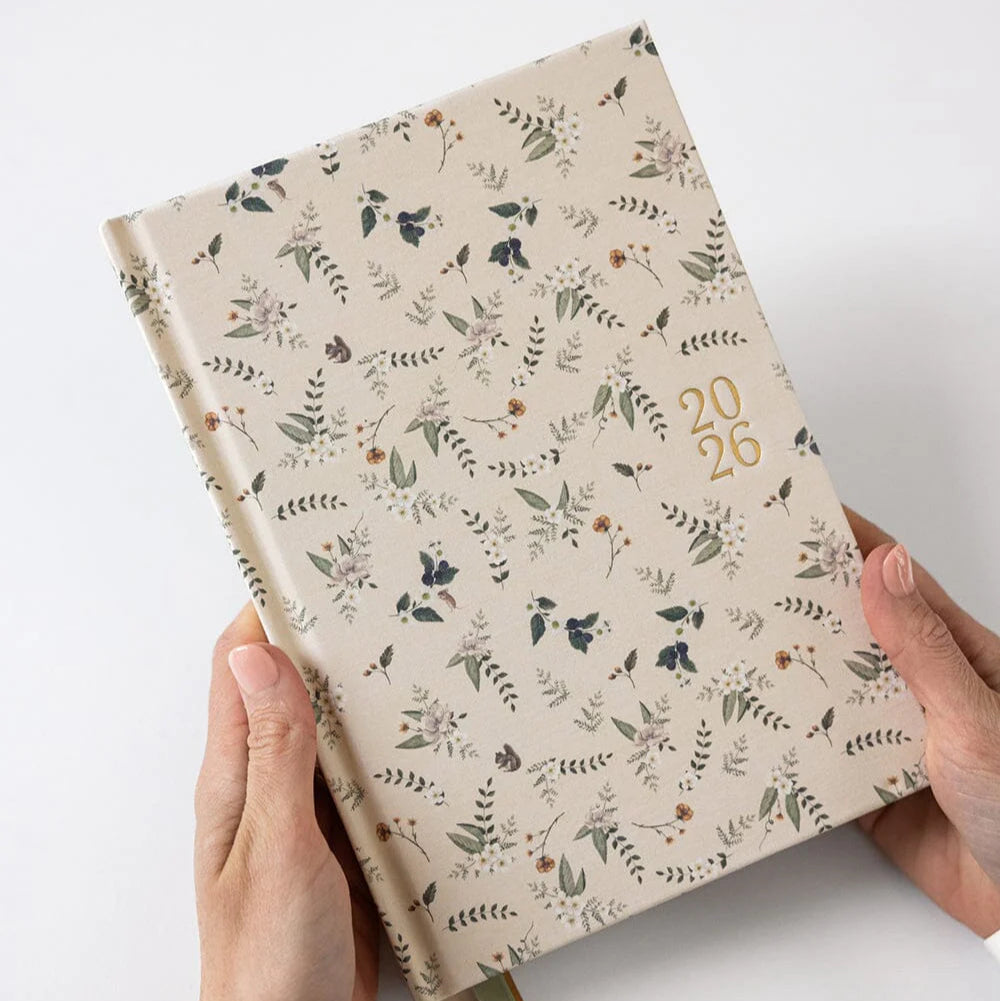 Floral-patterned notebook held by hands on a white background