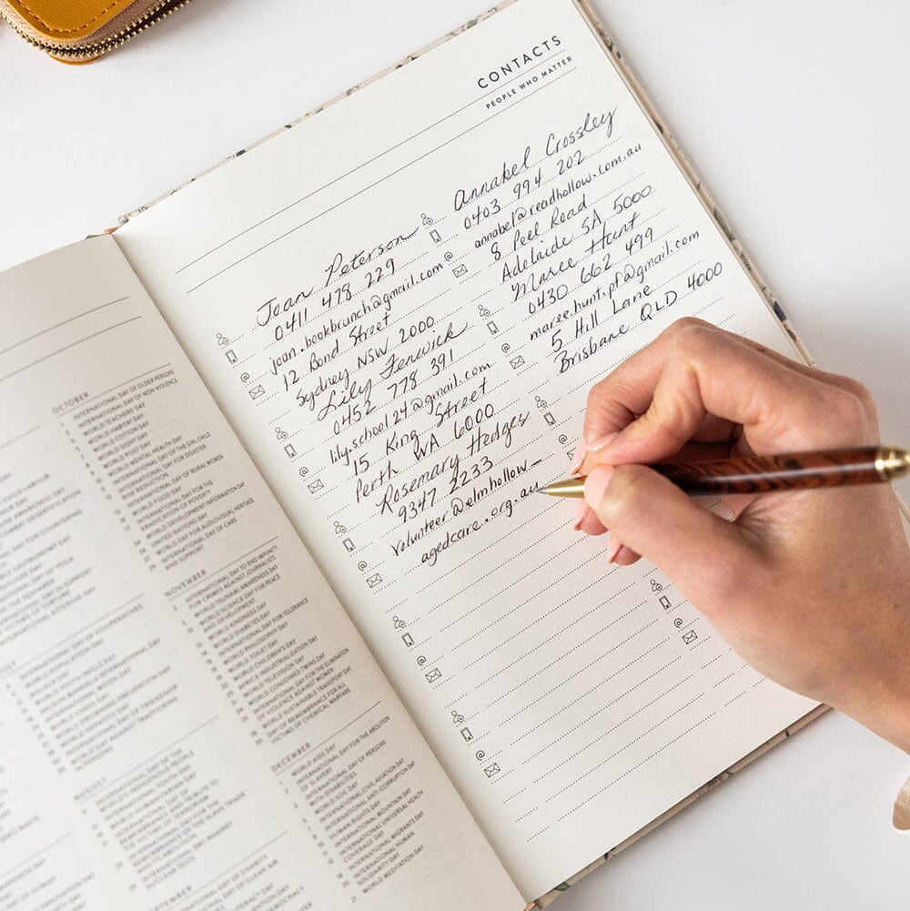 Hand writing in a notebook with a pen on a white surface