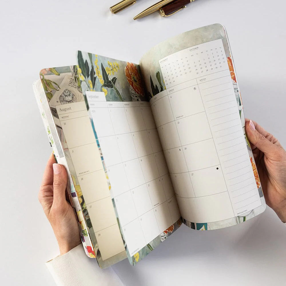 Open planner with floral design on a white surface