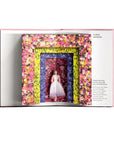 Open book displaying a colorful floral frame with a dress inside, on a white background.
