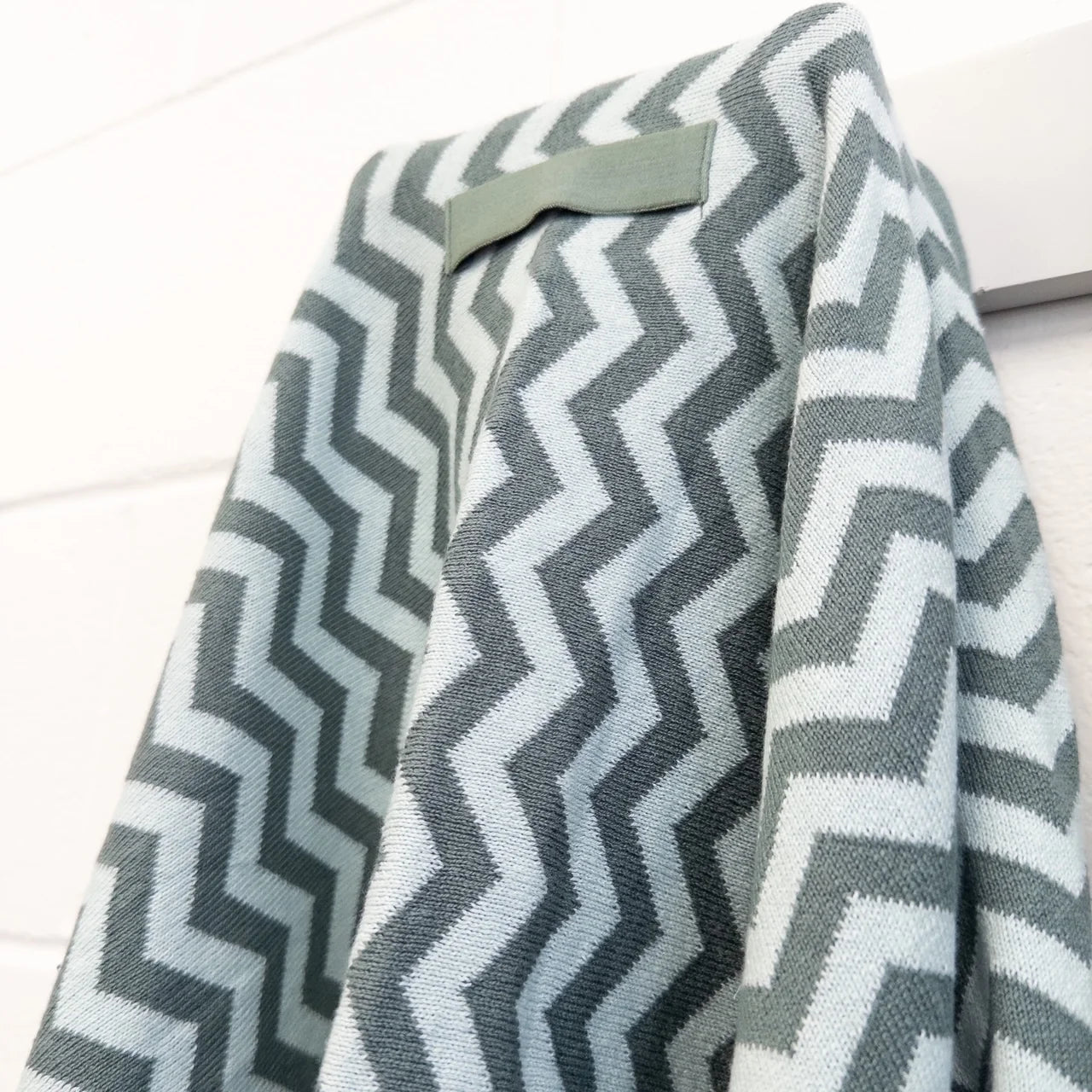 Gray and white chevron patterned blanket draped over a surface.