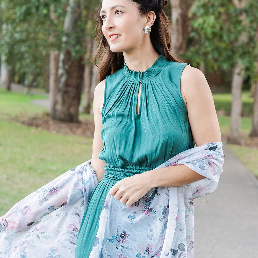 Woman in a teal dress with a floral scarf in a park setting
