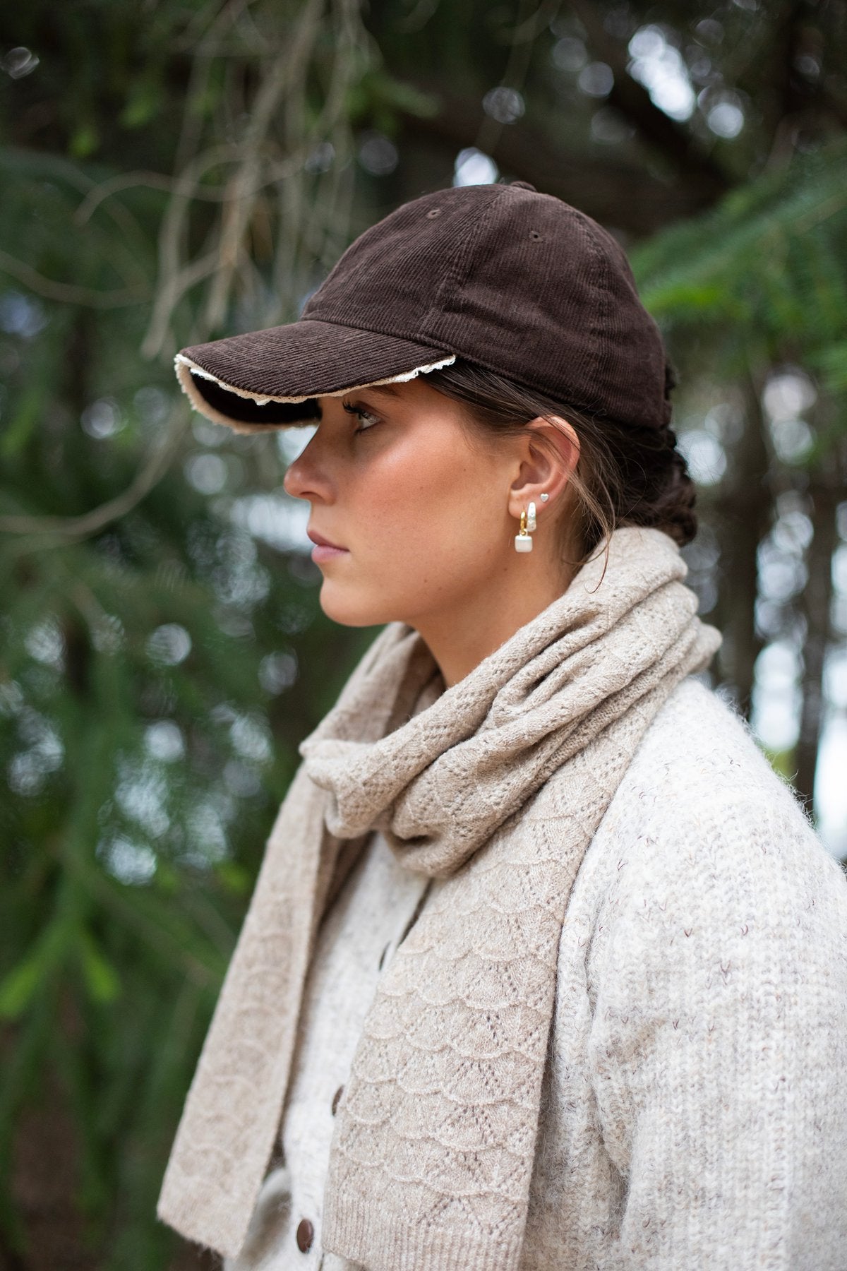 Woman wearing a brown cap and beige scarf outdoors