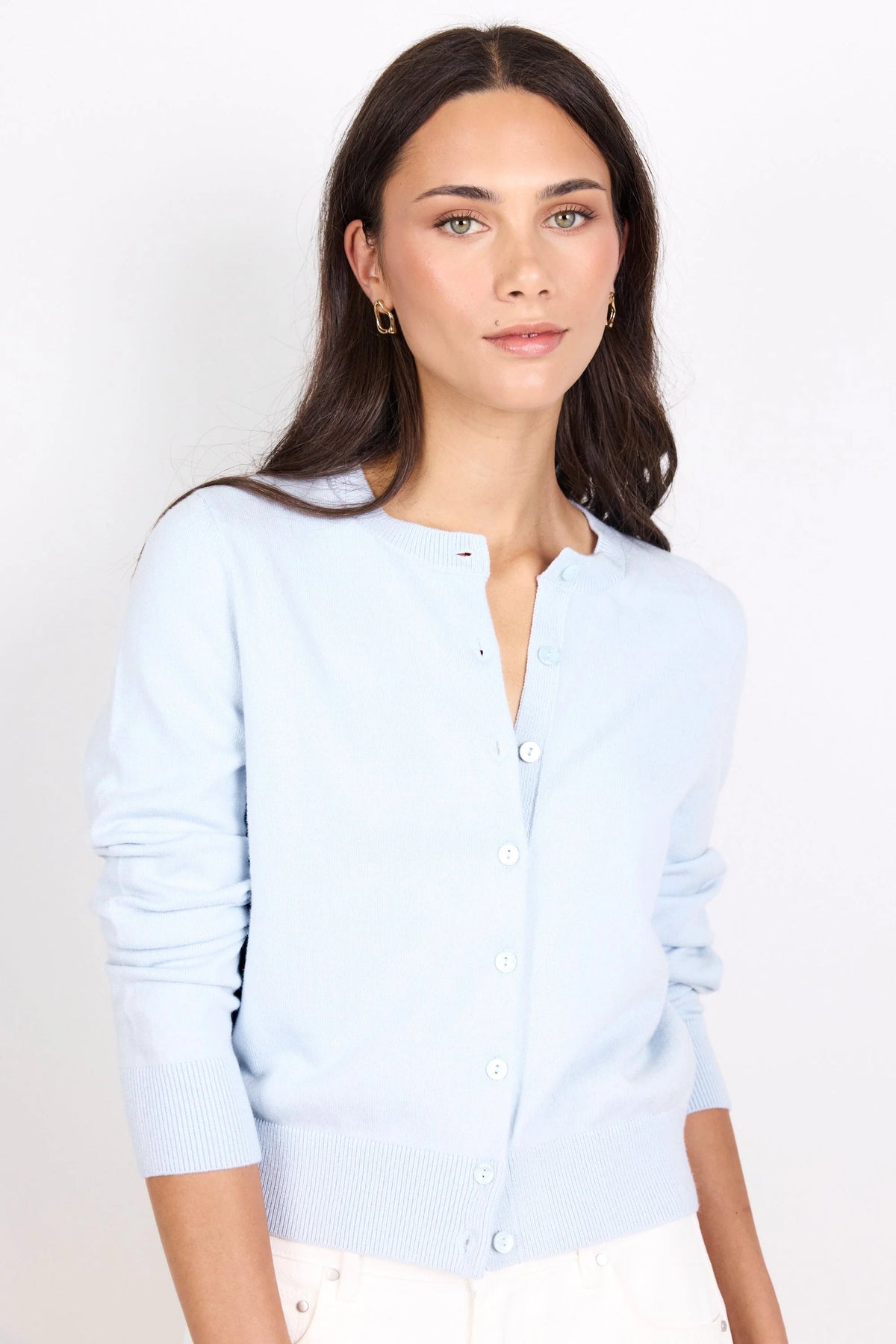 A woman modeling a light blue long-sleeve button-front cardigan sweater against a plain white studio background.