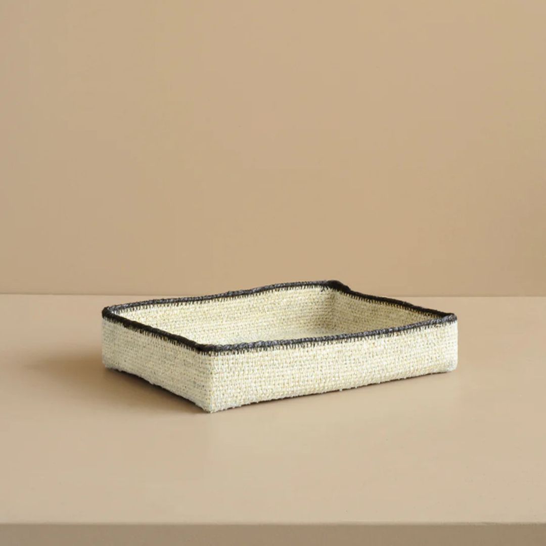 Rectangular woven tray with black rim on a beige background