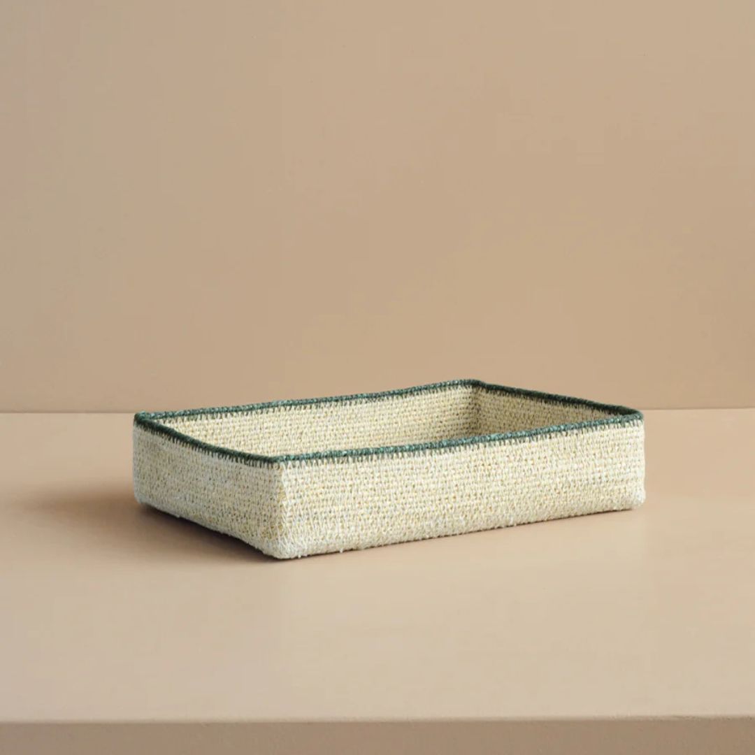 Rectangular woven basket with green rim on a beige background
