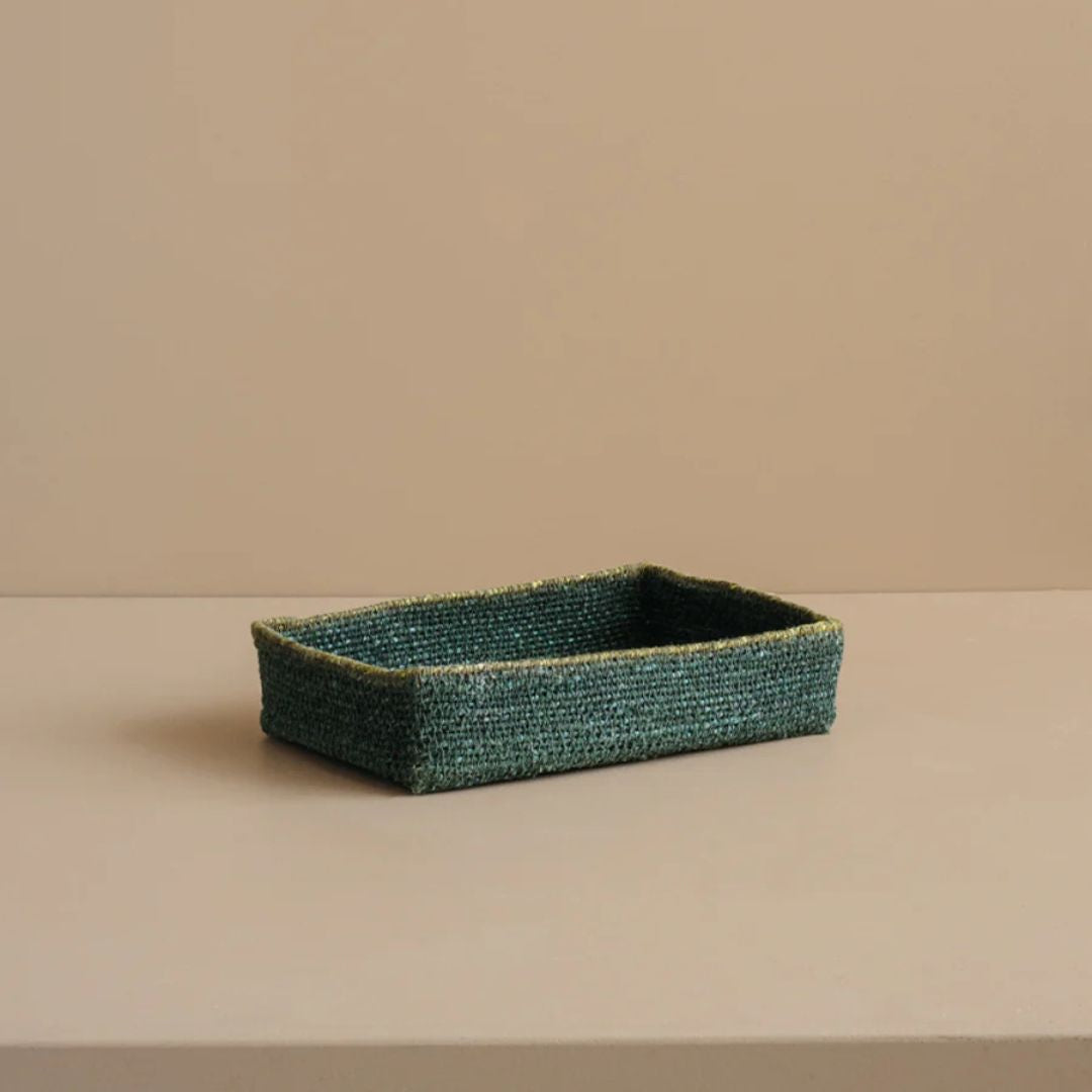 Green woven rectangular tray on a beige surface with a beige background