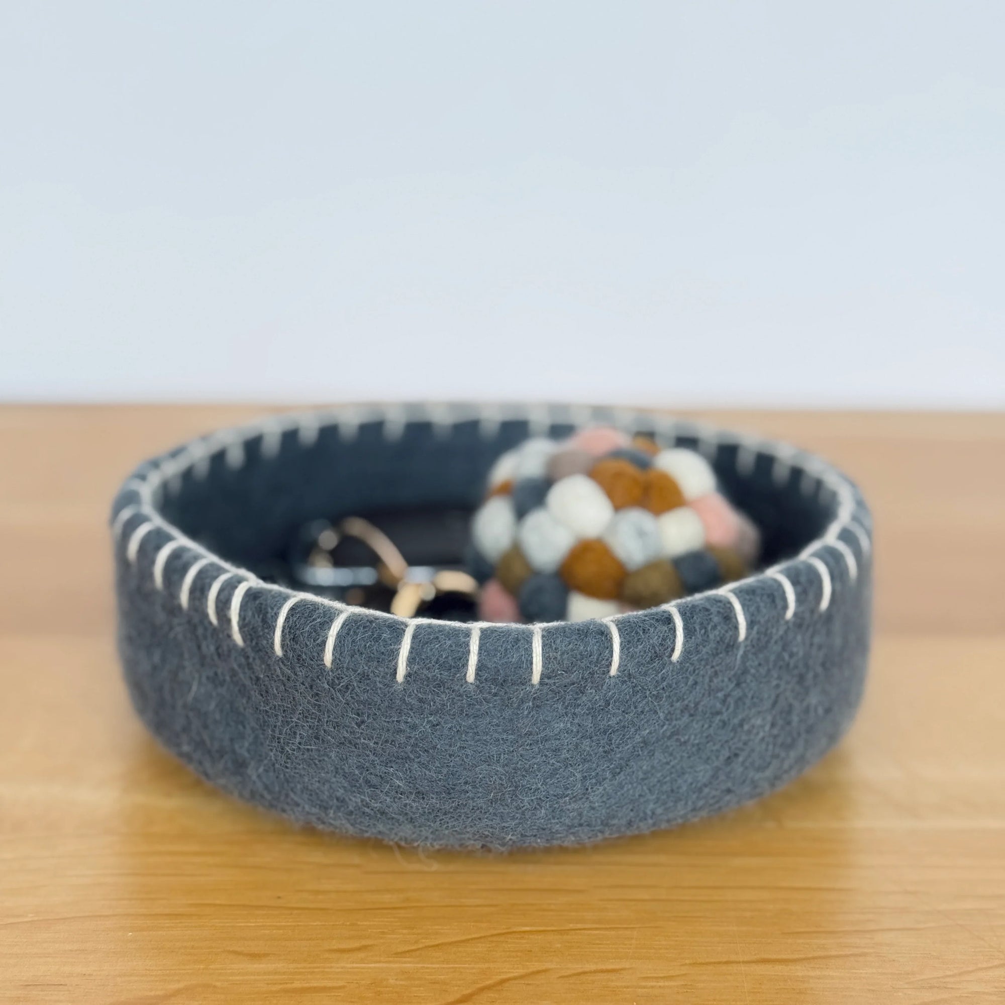 Blue felted bowl with decorative items on a wooden surface