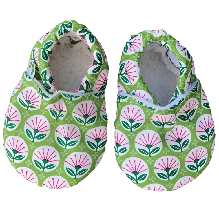 Pair of green baby shoes with floral pattern on a white background