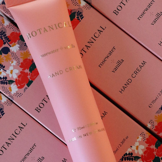 Pink hand cream tube and packaging with floral design on a matching pink background