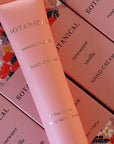 Pink hand cream tube and packaging with floral design on a matching pink background